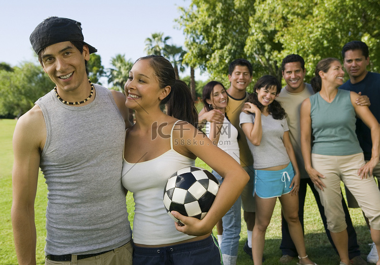年轻夫妇和女人在背景中拿着足球