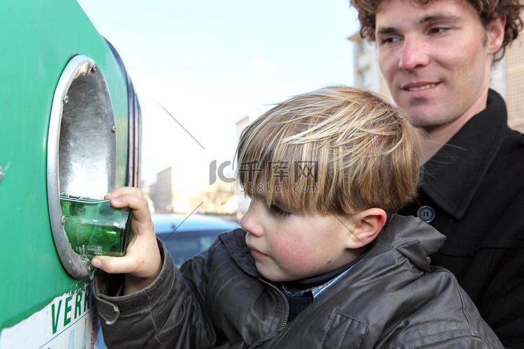 小男孩把玻璃瓶放进回收箱