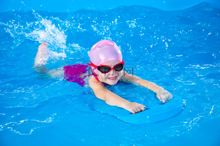 微笑的小女孩在游泳课上用颤音板