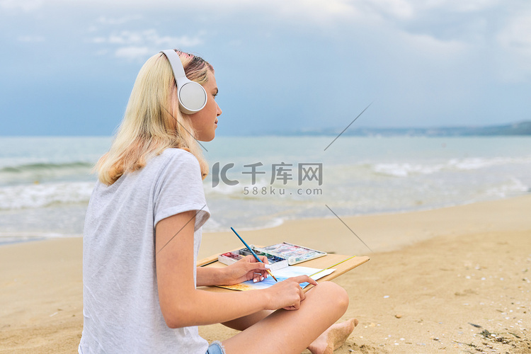 坐在海边用水彩画的年轻女画家