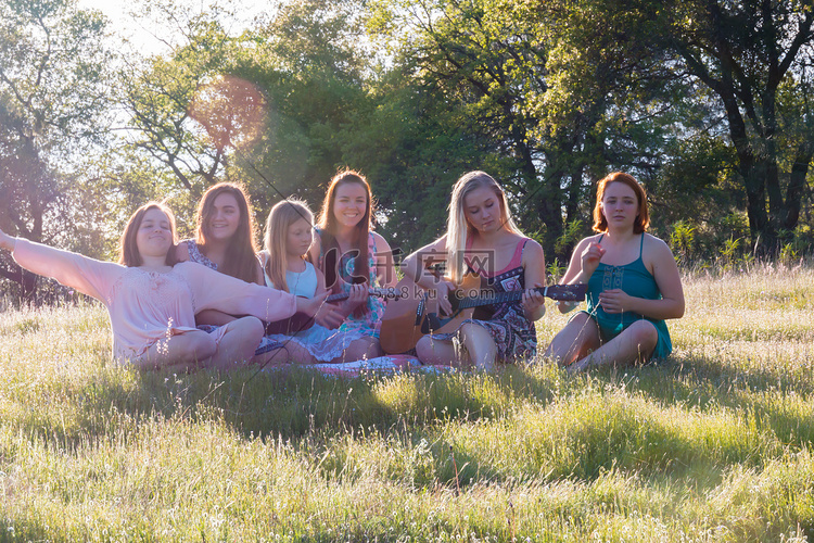 女孩们坐在一起在草地上唱歌和演