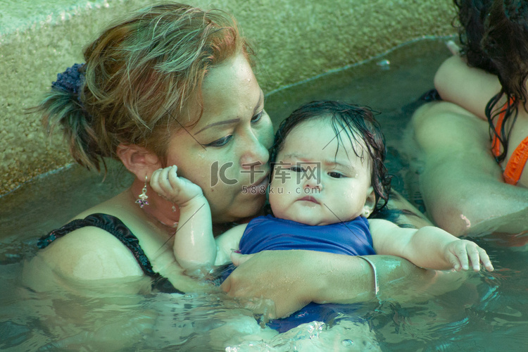 母亲在水中带着她的小女儿教游泳