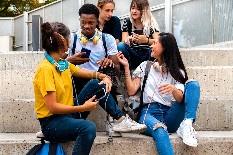 快乐的多种族青少年高中生坐在外
