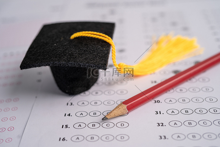 答卷背景上的毕业差距帽子和铅笔