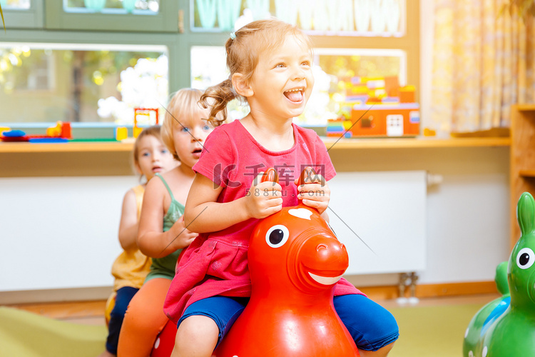 幼儿园里骑着玩马的小女孩