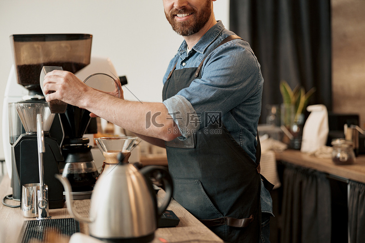 咖啡师的特写将咖啡豆倒入咖啡机