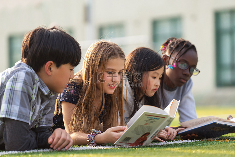 可爱的小学生们趴在草地上看书