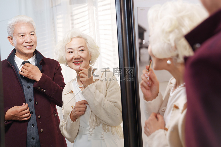 时尚的老年夫妇对着镜子穿衣打扮