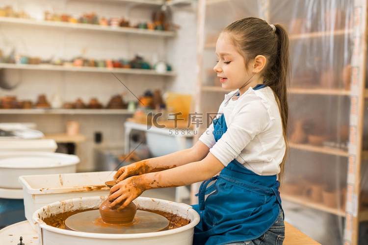 美丽的小女孩在陶艺作坊做一壶黏