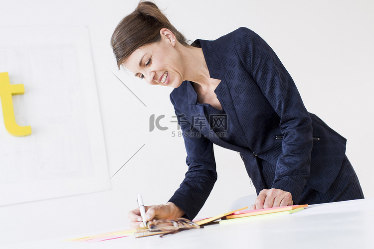 成熟的女人穿着商务装在文件上写