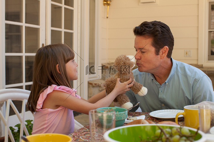 小女孩抱着泰迪熊等着爸爸亲吻