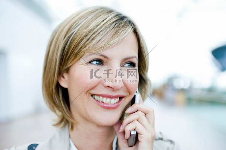 一位面带微笑的女人在讲手机