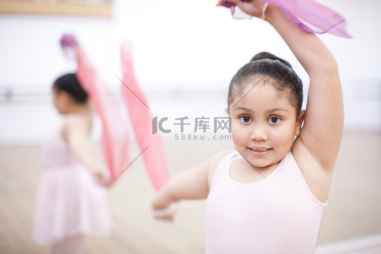 年轻芭蕾舞女演员戴着粉色围巾跳