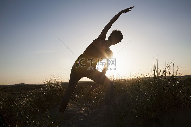日落时分中年妇女在长草上练习瑜