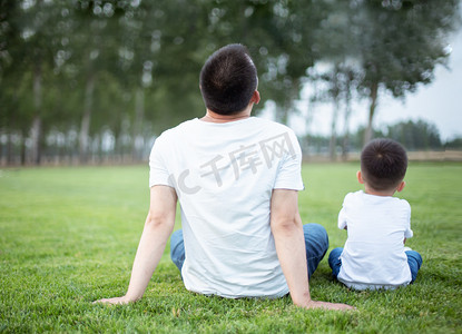 水彩熊父子摄影照片_坐在草地上的父子背影