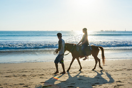 骑马放羊摄影照片_金巴兰海滩骑马的游客