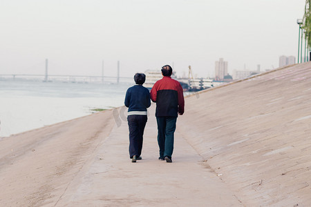 夫妇散步河岸背影摄影图