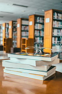 高考摄影照片_图书馆里书桌上的一摞书与眼镜框