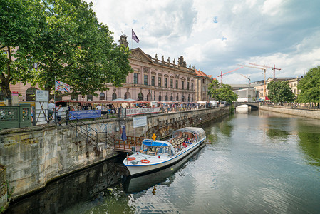 周末柏林运河岸边集市与河面游船摄影图