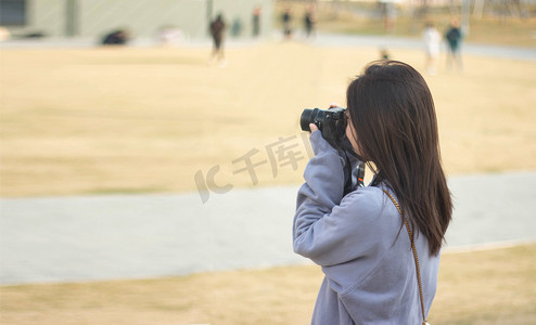 背景人物摄影照片_学习拍照的女生