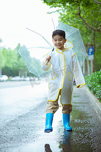 穿雨衣撑伞大步走的男孩