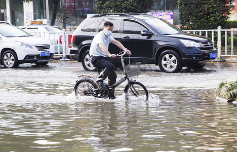 洪水洪涝下的城市骑自行车淹水的街道摄影图