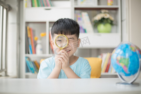 小孩抽筋摄影照片_用放大镜看地球仪的小男孩人物