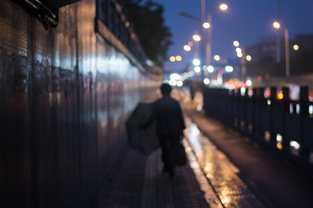 暖色调人物图像摄影照片_都市夜晚拿伞模糊背影