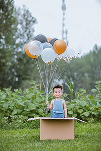 气球摄影照片_草地上玩气球的小男孩