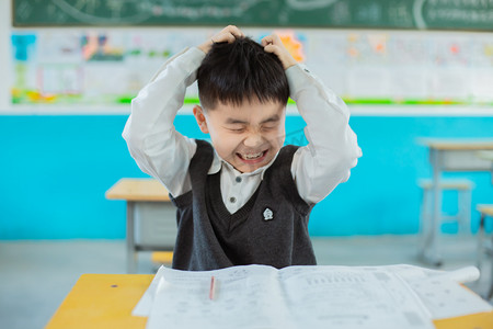 学生务农摄影照片_在教室抱头抓狂的学生