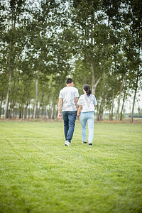 在草地上手拉手散步的情侣