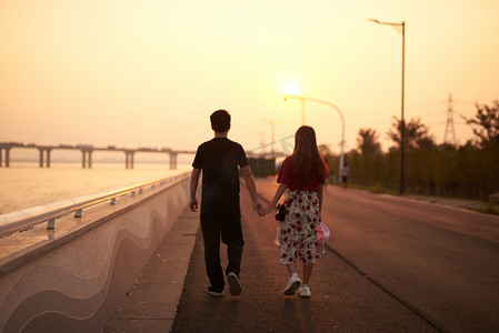 情侣傍晚摄影照片_傍晚江边散步的情侣摄影图