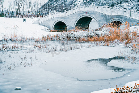 大寒雪地摄影照片_大雪过后雪地中的冰面和石桥风光