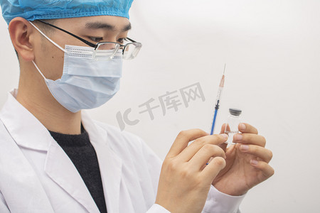 药水摄影照片_戴口罩的医生调试疫苗剂量摄影图