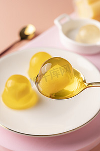 勺子黄色摄影照片_果冻白天果冻桌子舀起摄影图配图