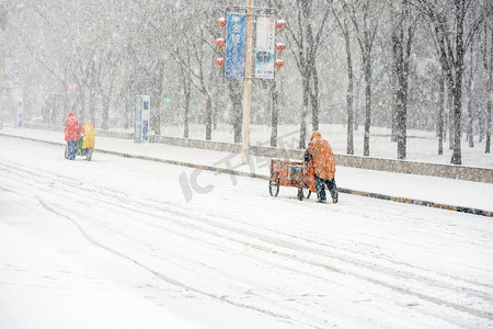 下雪天白天雪地上的保洁员道路行走摄影图配图