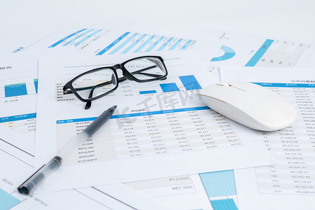 桌子桌面摄影照片_商务金融棚拍财务图表上的鼠标和眼镜金融概念图静物摄影图配图