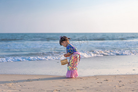 捡贝壳的小姑娘背影下午女孩背影海边捡摄影图配图