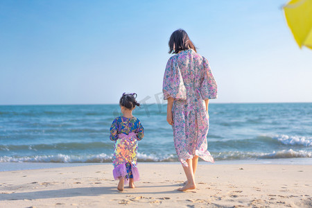 海面贴图摄影照片_海边的花姑娘下午妈妈和小女儿沙滩散步摄影图配图