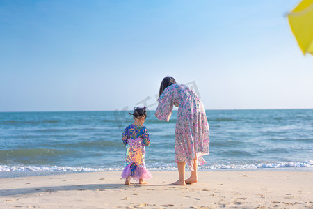 摄影照片_沙滩上的美人鱼母女下午妈妈和美人鱼宝宝海滩玩沙摄影图配图