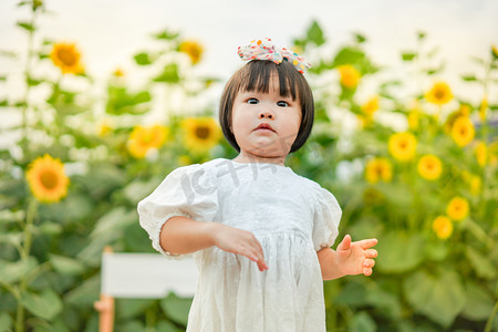 小孩奔跑摄影照片_儿童孩子向日葵花海傍晚女孩儿童两岁户外奔跑摄影图配图