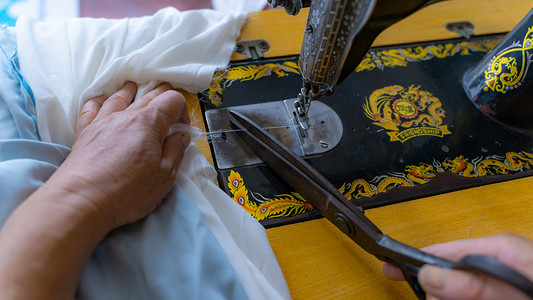 裁缝做衣服八十年代裁缝师缝纫机剪线头摄影图配图