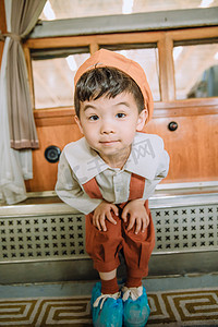 文艺复古儿童白天穿着背带裤的小男孩火车站里望镜头摄影图配图