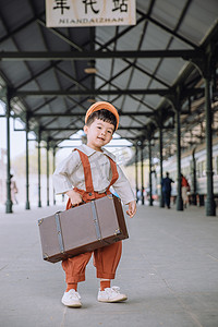 复古文艺儿童白天小男孩火车站提着行李箱摄影图配图