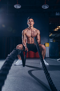 健身减脂夜晚健身的肌肉男健身房战绳摄影图配图