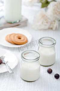 饼干酸奶摄影照片_美食白天两杯酸奶白色桌子上摆放摄影图配图