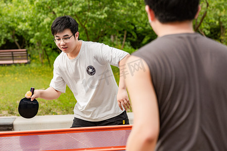 乒乓球乒乓球摄影照片_运动白天打球的男孩户外打乒乓球摄影图配图