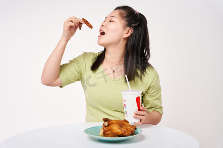肥胖不健康肥胖女孩吃烤鸡喝汽水摄影图配图