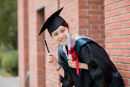 毕业季白天穿着学士服的女学生户外摆拍摄影图配图