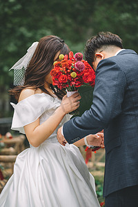鲜花布置摄影照片_婚礼白天在婚礼现场的新郎新娘户外草坪整理服装摄影图配图